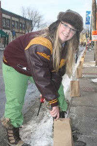 Maddi Miller, a member of the National Honor Society & Northfield High School Class of 2014, volunteers to light luminaria candles set up along Division Street